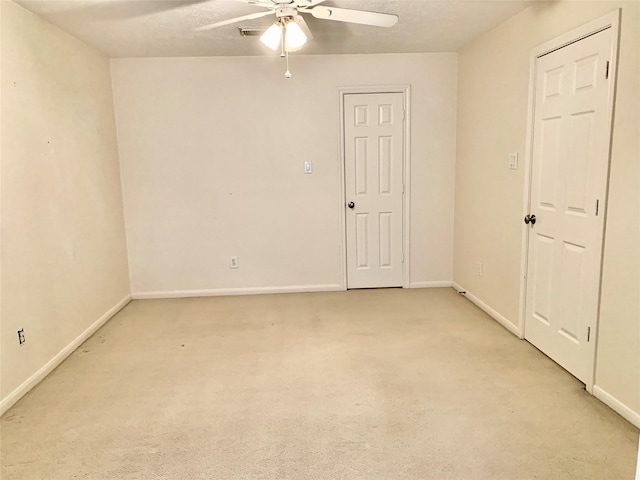 spare room featuring ceiling fan, light carpet, and a textured ceiling