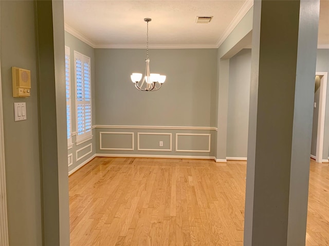 unfurnished dining area with a chandelier, ornamental molding, and light hardwood / wood-style flooring