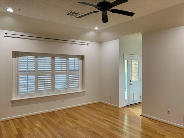 unfurnished room featuring plenty of natural light, light hardwood / wood-style floors, and a textured ceiling