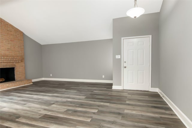 unfurnished living room featuring brick wall, a brick fireplace, lofted ceiling, and hardwood / wood-style floors