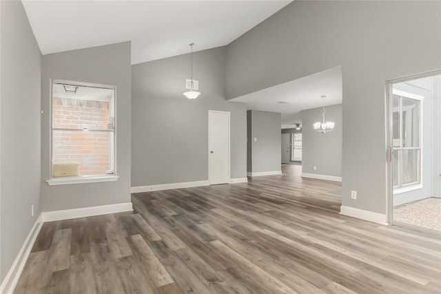 interior space with wood-type flooring, a notable chandelier, a wealth of natural light, and high vaulted ceiling