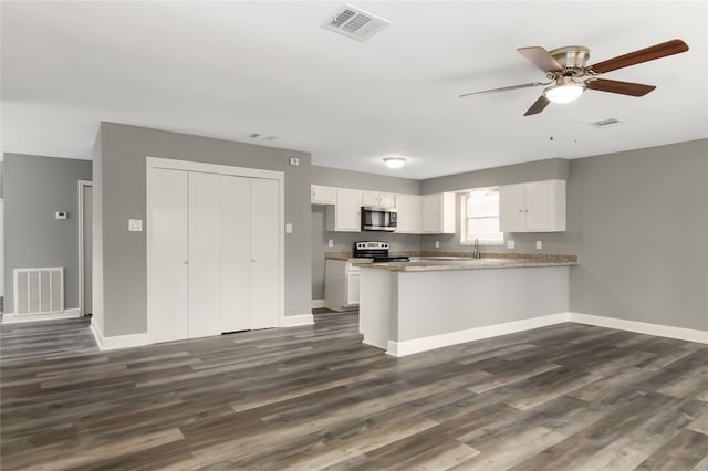 kitchen featuring dark hardwood / wood-style floors, white cabinetry, appliances with stainless steel finishes, and kitchen peninsula