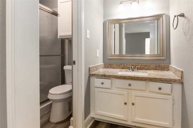 bathroom with walk in shower, toilet, hardwood / wood-style floors, and vanity