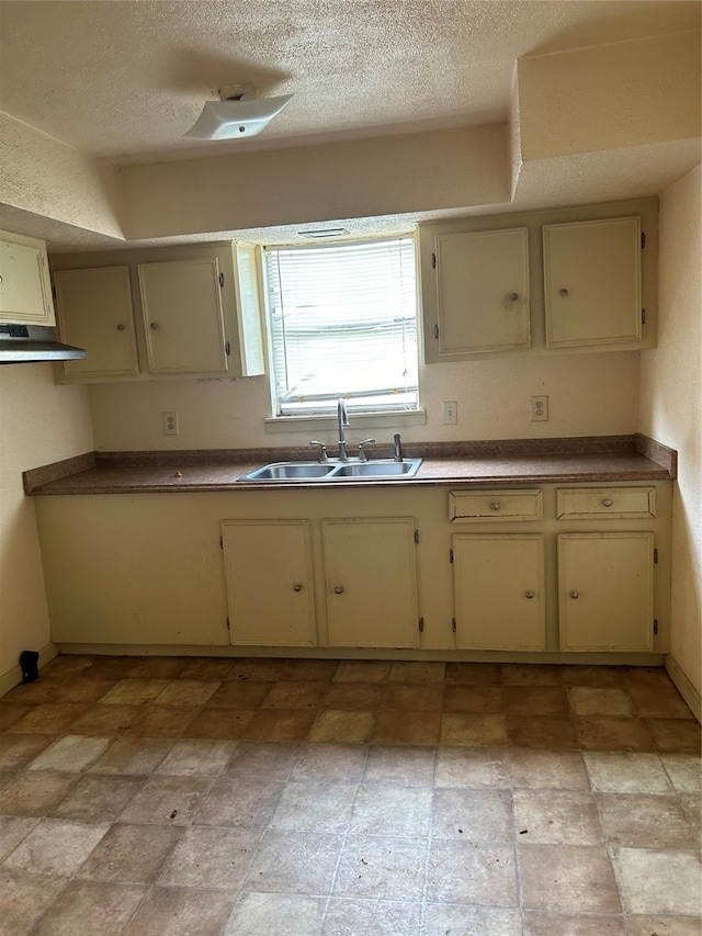 kitchen with sink, a textured ceiling, cream cabinets, and light tile floors