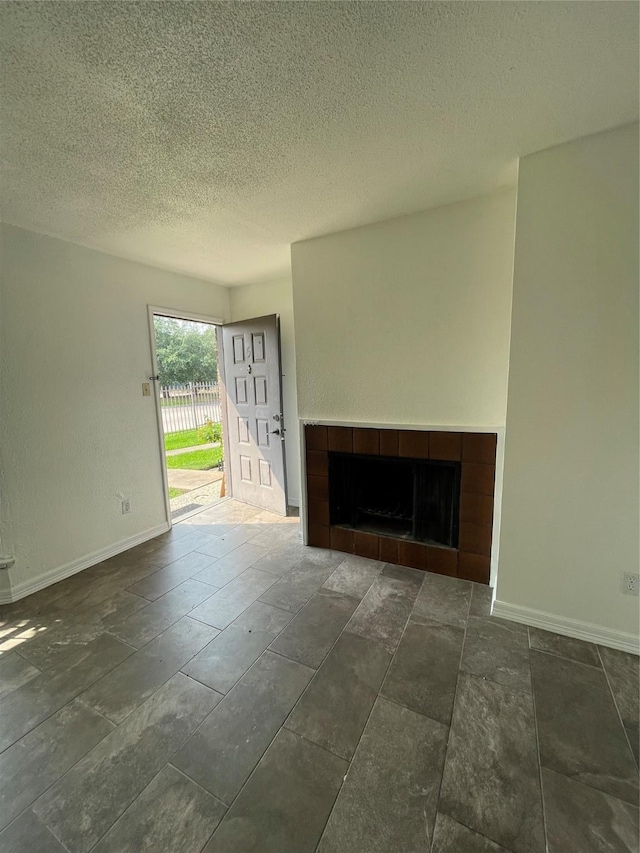 unfurnished living room featuring a textured ceiling and a tiled fireplace