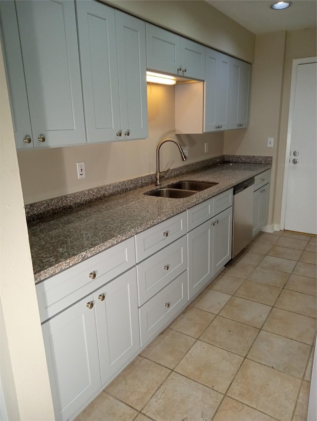 kitchen with sink, light tile patterned floors, dark stone countertops, and dishwasher