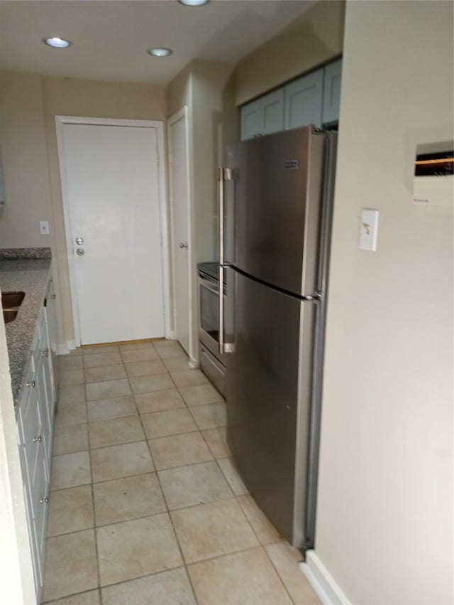 kitchen with light tile patterned floors, light stone counters, and appliances with stainless steel finishes