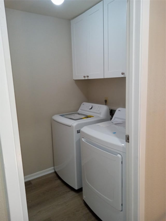 clothes washing area with dark hardwood / wood-style flooring, cabinets, and washer and clothes dryer