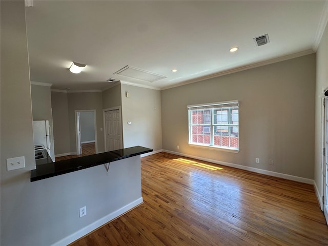 kitchen featuring a kitchen bar, kitchen peninsula, light hardwood / wood-style flooring, and ornamental molding