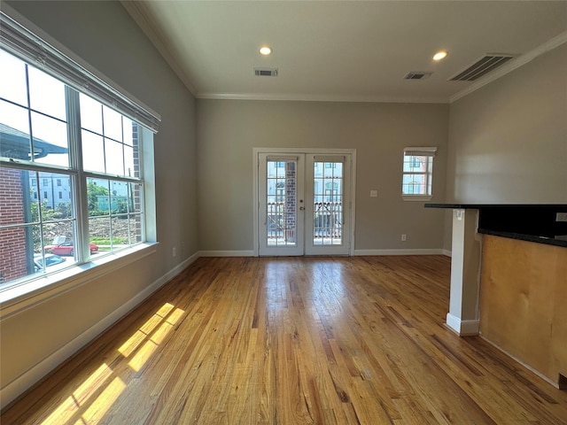 unfurnished living room with ornamental molding, french doors, a healthy amount of sunlight, and light hardwood / wood-style flooring