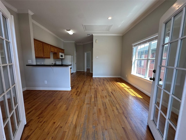 kitchen featuring kitchen peninsula, hardwood / wood-style floors, white appliances, and ornamental molding