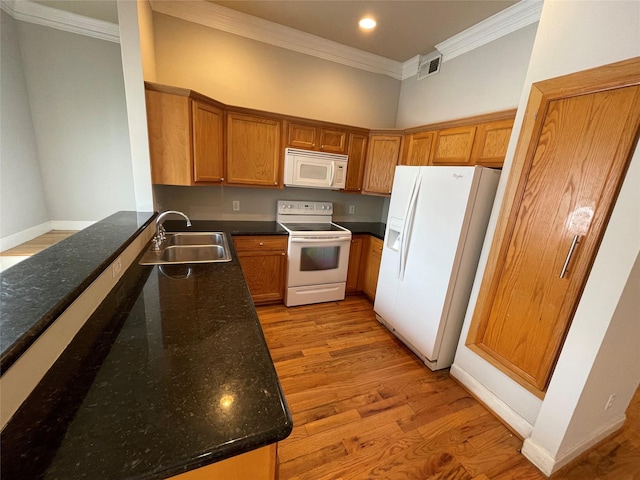 kitchen with light wood-type flooring, white appliances, crown molding, sink, and dark stone countertops