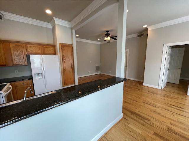 kitchen featuring white appliances, dark stone counters, crown molding, ceiling fan, and light hardwood / wood-style floors