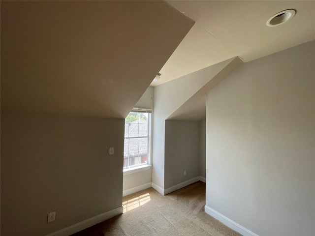 additional living space with light colored carpet and vaulted ceiling