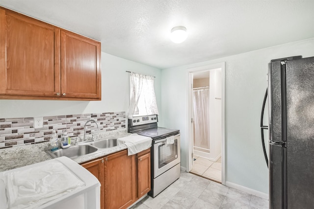 kitchen with stainless steel electric range, black fridge, sink, decorative backsplash, and a textured ceiling