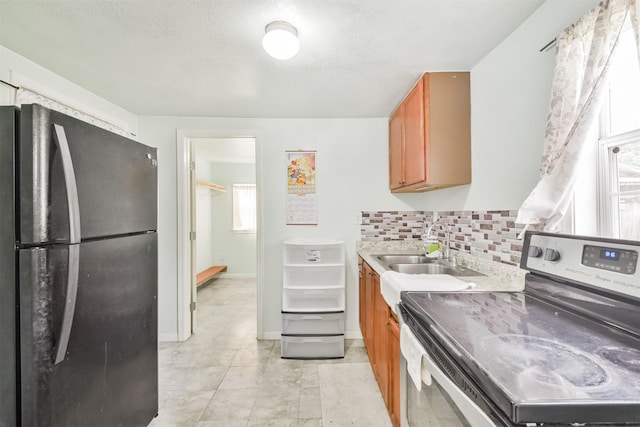 kitchen featuring tasteful backsplash, black fridge, a textured ceiling, sink, and electric range