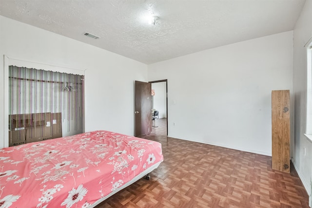 bedroom featuring a textured ceiling and parquet flooring