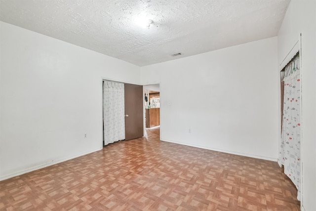 unfurnished room with a textured ceiling and light parquet floors