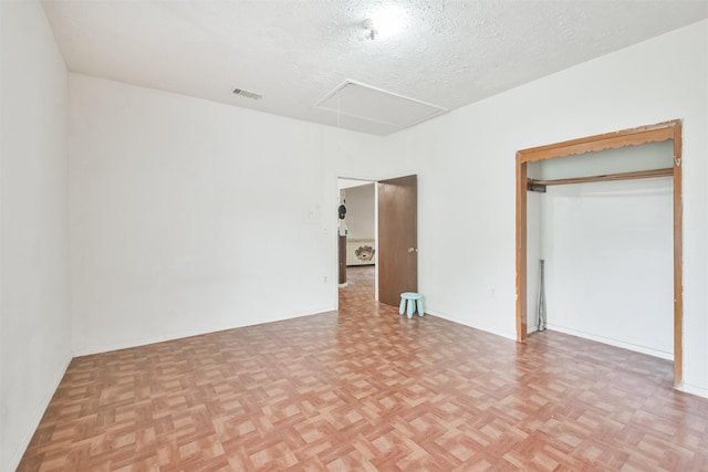 unfurnished bedroom featuring a closet, light parquet flooring, and a textured ceiling