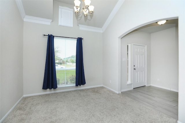 carpeted foyer with crown molding and an inviting chandelier