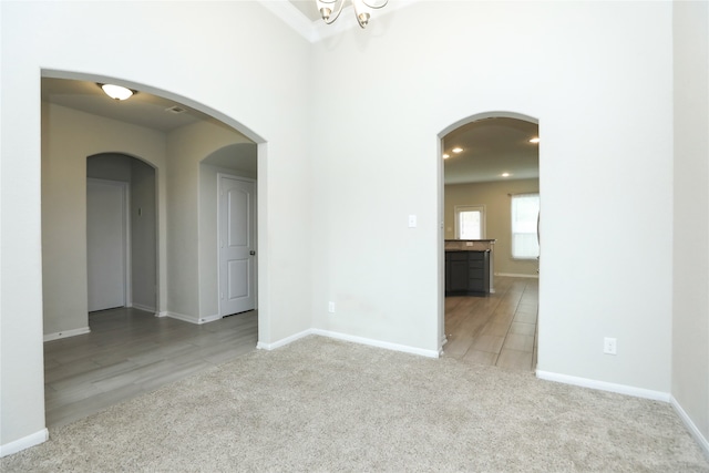 spare room with a notable chandelier and light wood-type flooring