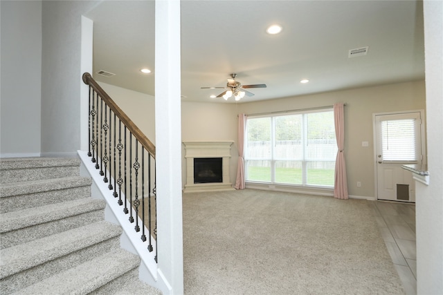 unfurnished living room featuring ceiling fan and light colored carpet