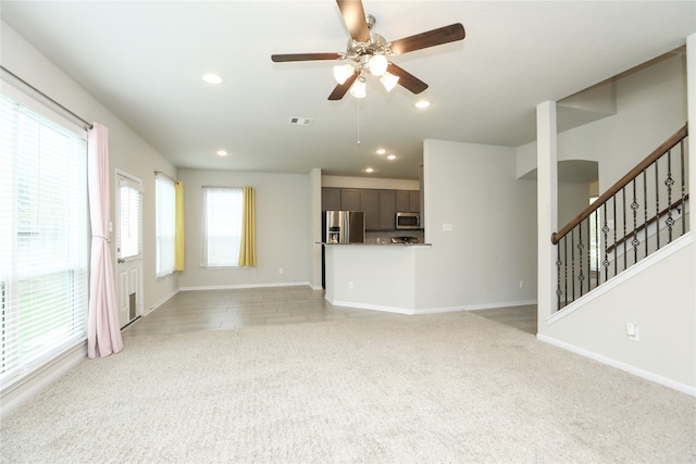 unfurnished living room featuring ceiling fan and light colored carpet