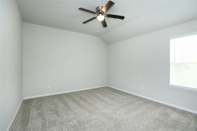 carpeted spare room featuring vaulted ceiling and ceiling fan