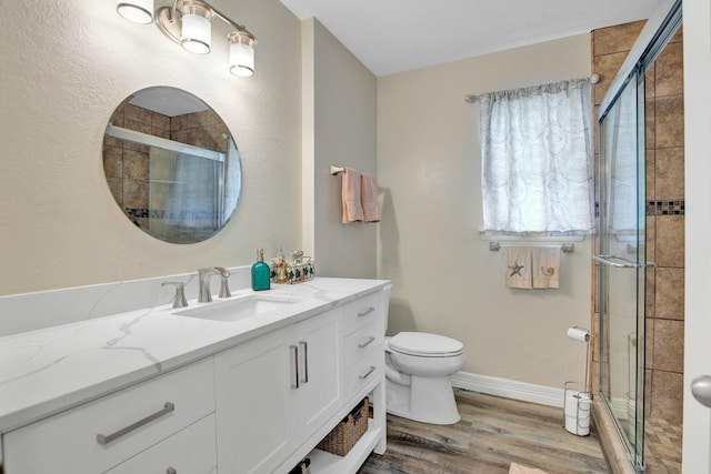 bathroom featuring vanity, hardwood / wood-style flooring, walk in shower, and toilet