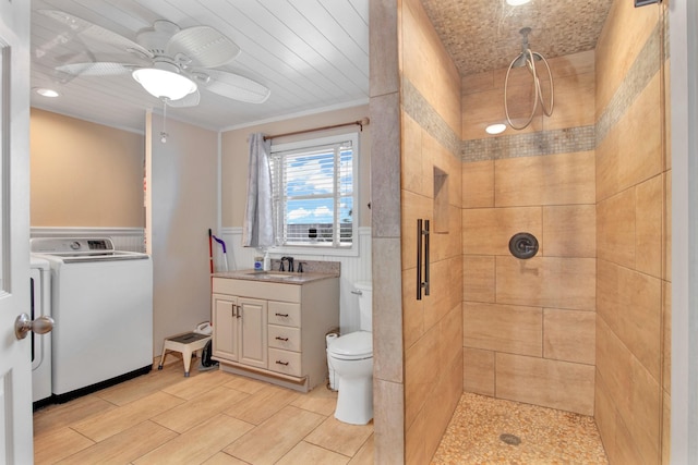 bathroom featuring toilet, washer / dryer, a tile shower, and vanity