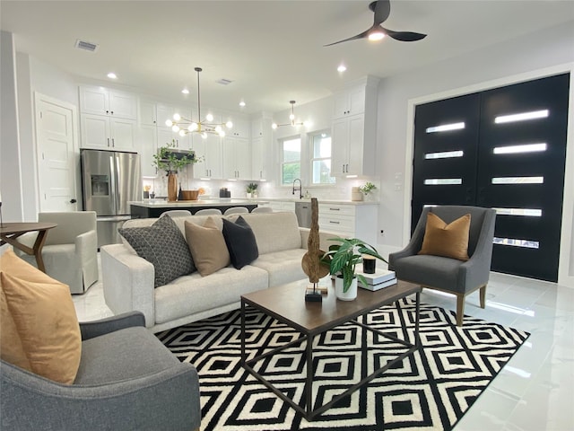 living room featuring ceiling fan with notable chandelier and sink