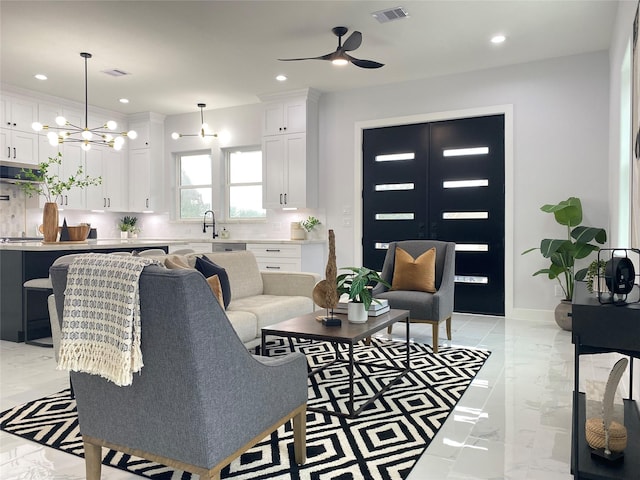 living room featuring sink and ceiling fan with notable chandelier