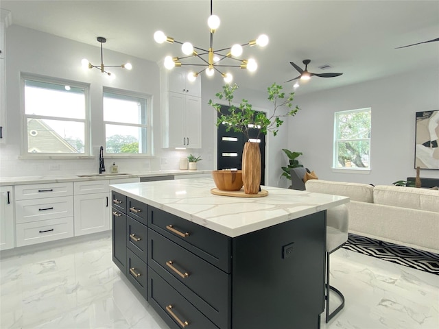 kitchen with pendant lighting, a center island, sink, and white cabinets