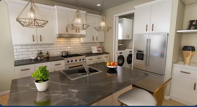 kitchen featuring backsplash, washer and clothes dryer, high end appliances, a center island, and white cabinets