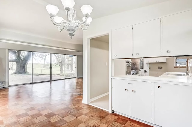 kitchen featuring white cabinets, an inviting chandelier, and sink