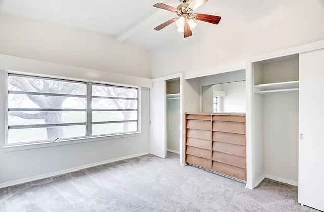 unfurnished bedroom with ceiling fan, light carpet, multiple closets, and beam ceiling