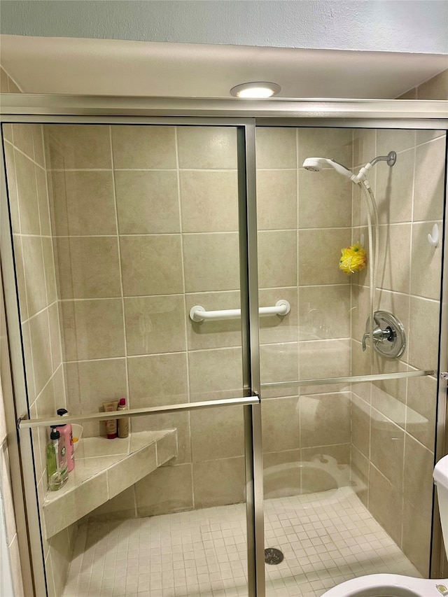 bathroom featuring a shower with shower door and toilet