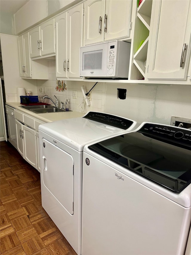 laundry room featuring dark parquet floors, sink, and washer and clothes dryer