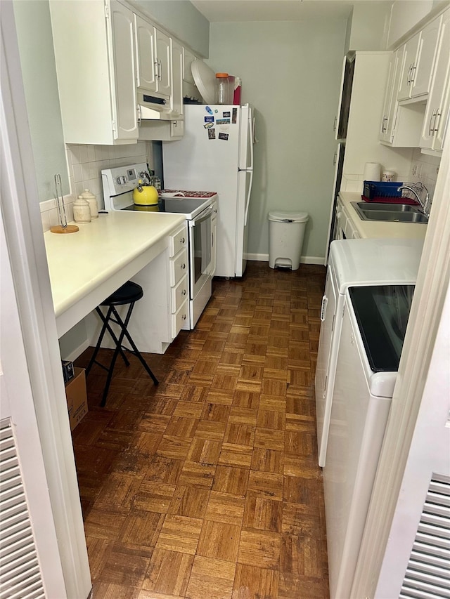 kitchen with dark parquet floors, a kitchen breakfast bar, white electric stove, white cabinets, and sink