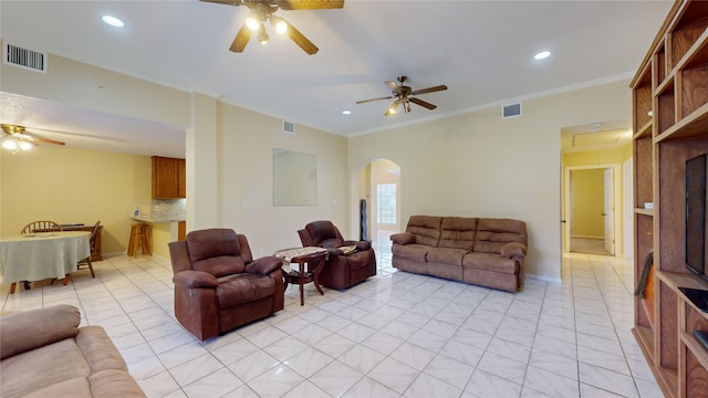 tiled living room with ceiling fan and crown molding