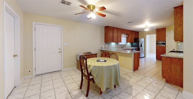 kitchen with kitchen peninsula, appliances with stainless steel finishes, backsplash, a textured ceiling, and ceiling fan