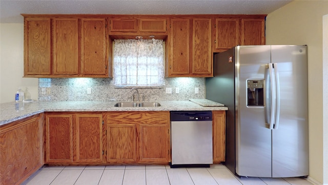 kitchen with light stone countertops, sink, stainless steel appliances, tasteful backsplash, and light tile patterned flooring