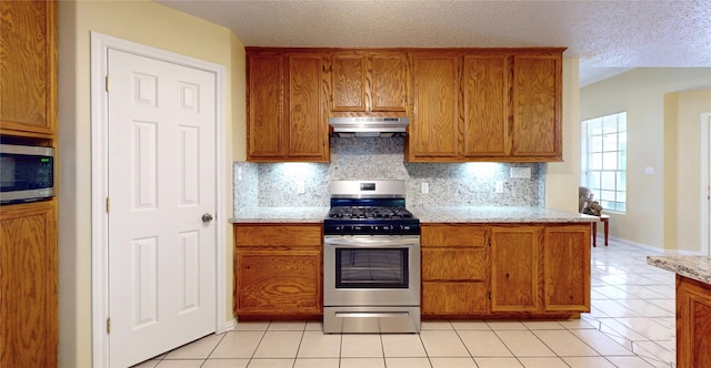 kitchen featuring decorative backsplash, light tile patterned floors, light stone counters, and appliances with stainless steel finishes