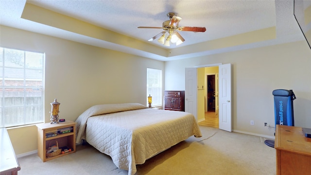 bedroom with a tray ceiling, ceiling fan, and light colored carpet