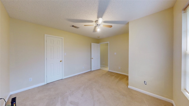 unfurnished bedroom with a textured ceiling, light colored carpet, and ceiling fan