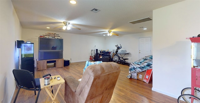 living room with ceiling fan, hardwood / wood-style floors, and a textured ceiling