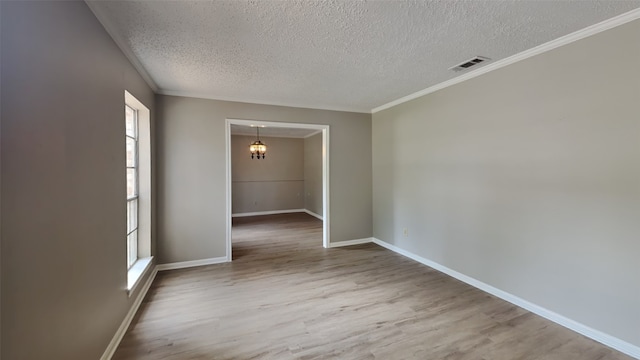 empty room with a healthy amount of sunlight, wood-type flooring, a textured ceiling, and an inviting chandelier