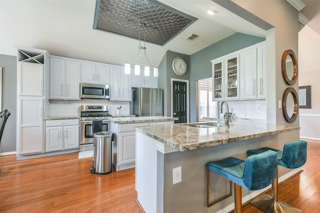 kitchen with kitchen peninsula, appliances with stainless steel finishes, backsplash, sink, and hanging light fixtures