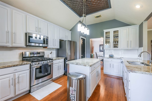 kitchen featuring white cabinets, decorative light fixtures, backsplash, and stainless steel appliances