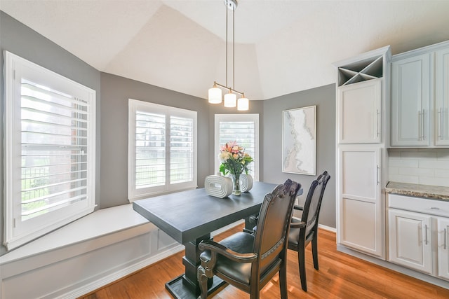 dining space featuring light hardwood / wood-style floors, an inviting chandelier, and lofted ceiling